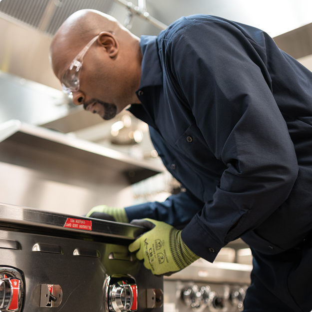 Service technician in safety glasses adjusting the controls of a commercial range