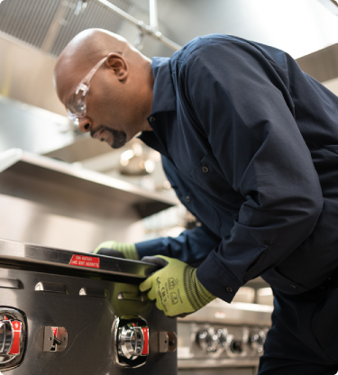 Service technician in safety glasses adjusting the controls of a commercial range