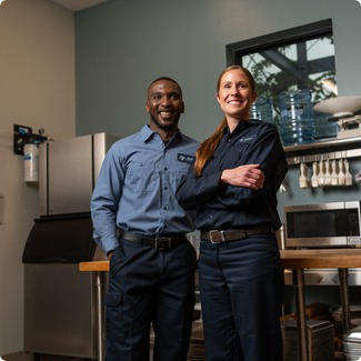 Two Allied Service Group technicians standing side by side with arms crossed in a commercial kitchen