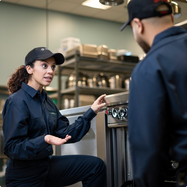Two Allied Service Group technicians talking beside equipment in a commercial kitchen