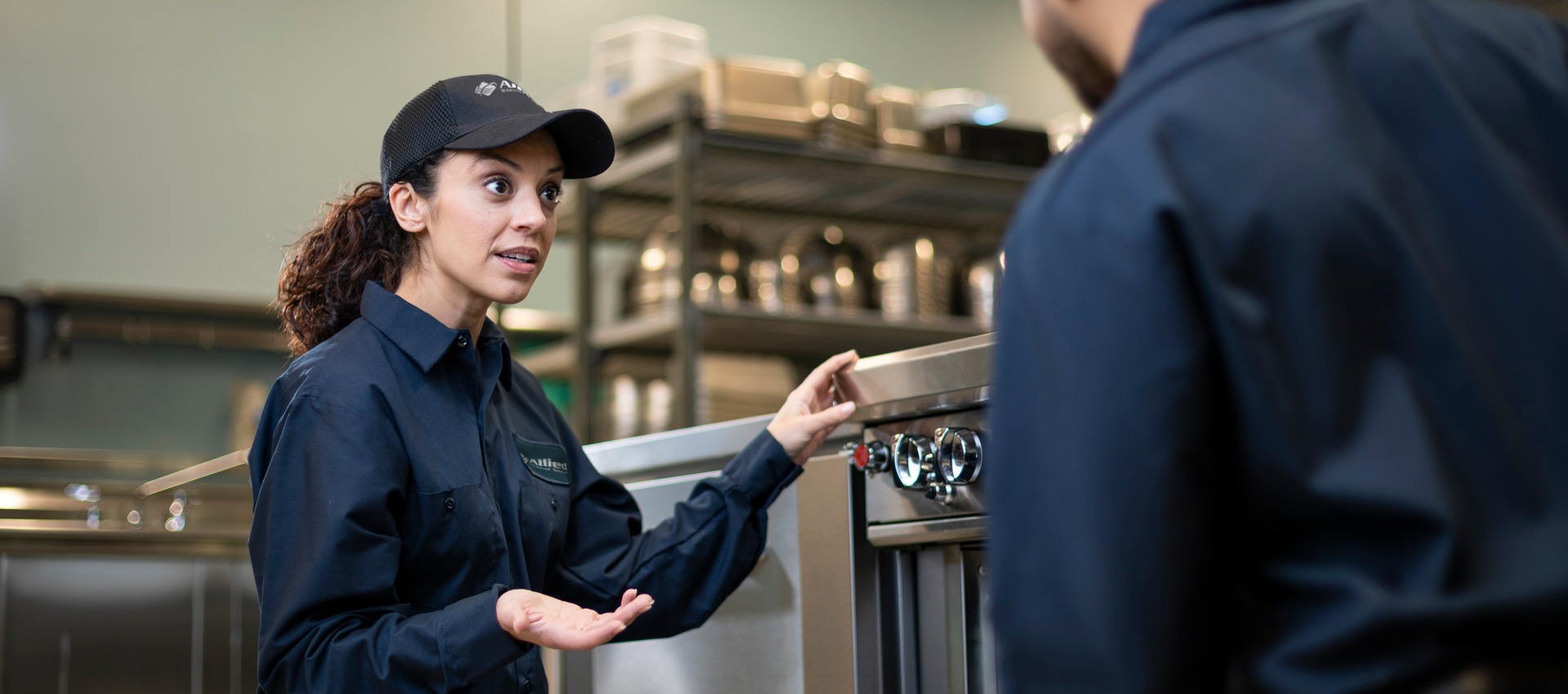 Two Allied Service Group technicians talking beside equipment in a commercial kitchen