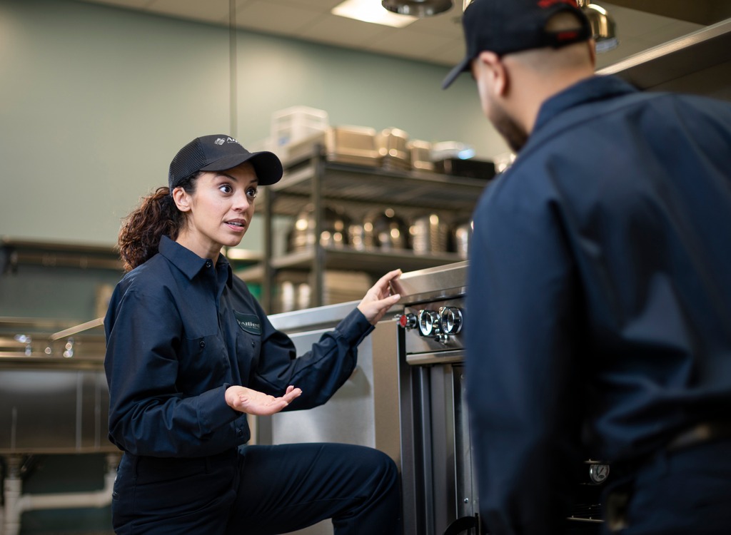 Two Allied Service Group technicians talking beside equipment in a commercial kitchen