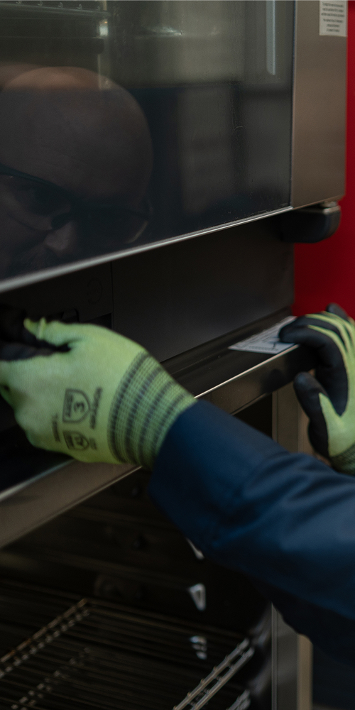 Service technician in safety glasses inspecting the door of a commercial oven