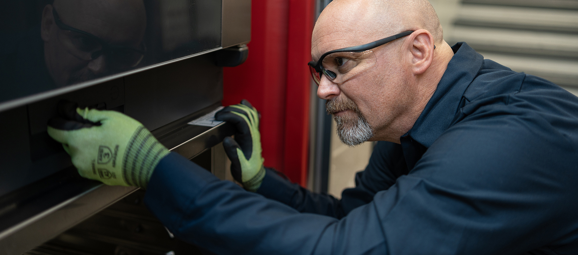 Service technician in safety glasses inspecting the door of a commercial oven