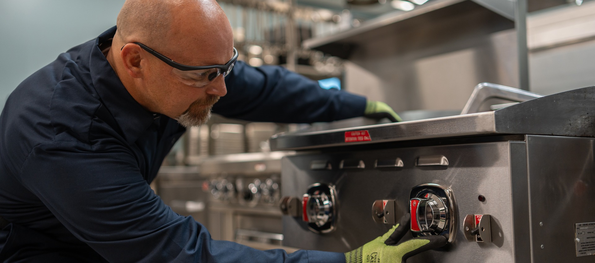 Allied Service Group technician adjusting the control knobs on a commercial range
