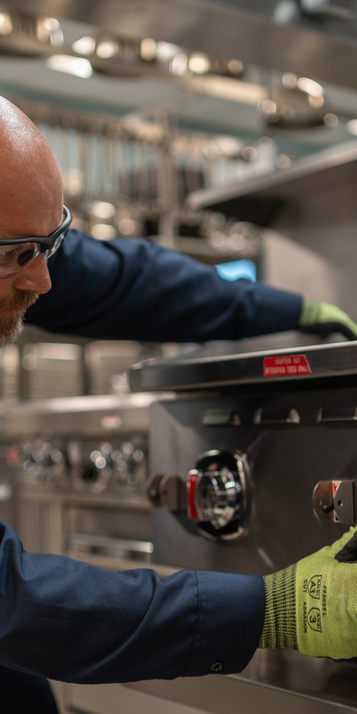 Allied Service Group technician adjusting the control knobs on a commercial range